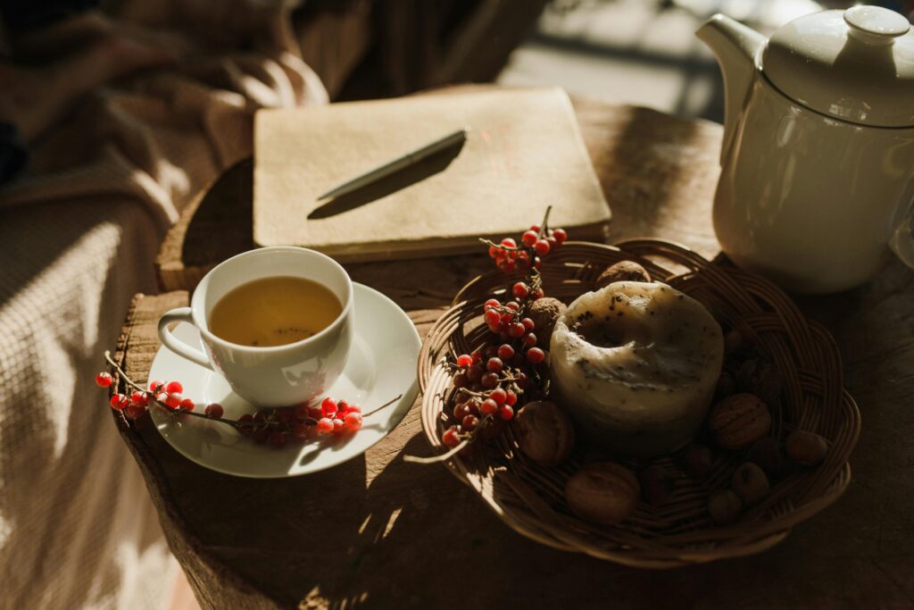 A cozy nighttime self-care ritual scene showing a mug of herbal tea, with natural sleep supplements neatly arranged on a bedside table, a book, soft blanket in the background, dim warm lighting creating a relaxing ambiance