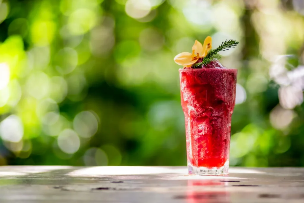 Glass of vibrant red fruit and vegetable smoothie garnished with fresh herbs, illustrating a natural liver detox drink made with nutrient-rich ingredients that support overall natural liver health as part of a balanced diet.
