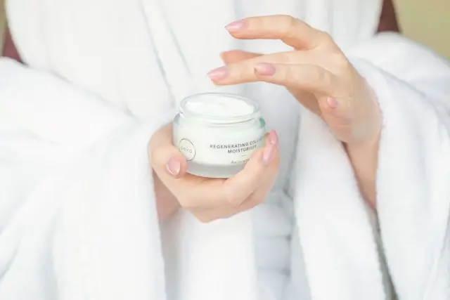 Woman holding a jar of moisturizer as part of an anti-aging skincare night routine for women over 50.