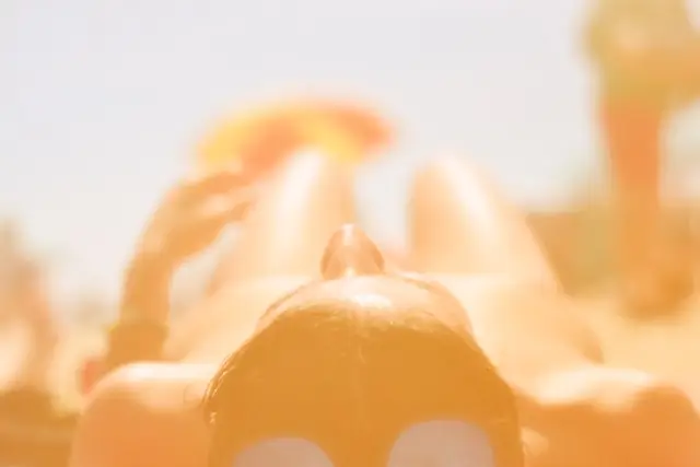Woman relaxing under bright sunlight with broad-spectrum sunscreen applied to protect her skin from UV rays, premature aging, wrinkles, and sun damage.
