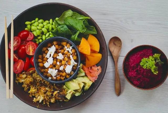 Mediterranean diet meal plan with colorful vegetable salads, avocado, legumes, and healthy whole-food dishes served on a dining table.