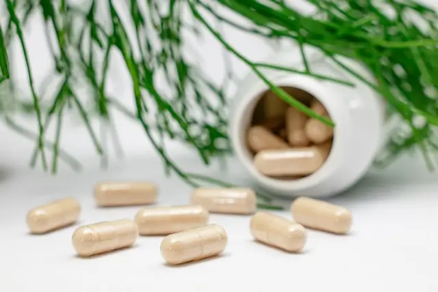 Dietary supplements in capsules scattered beside an open supplement container, representing supplements for metabolic health and weight management.
