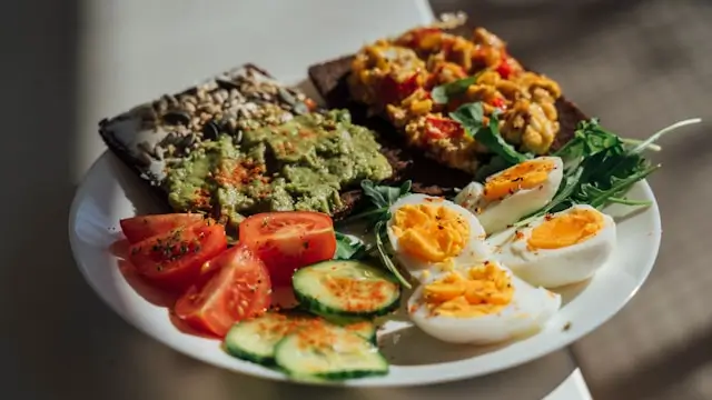Plate of protein-rich foods including boiled eggs, avocado toast, fresh vegetables, and leafy greens, illustrating satisfying low-calorie snack options that support fullness and healthy weight management.