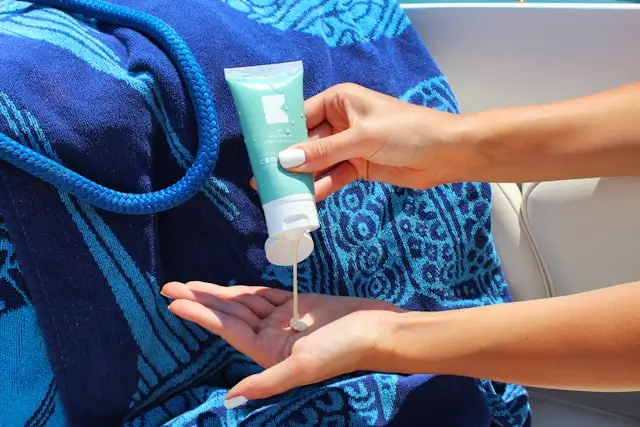 Person applying broad-spectrum sunscreen lotion onto their hand before sun exposure to help prevent premature skin aging, wrinkles, and UV damage.
