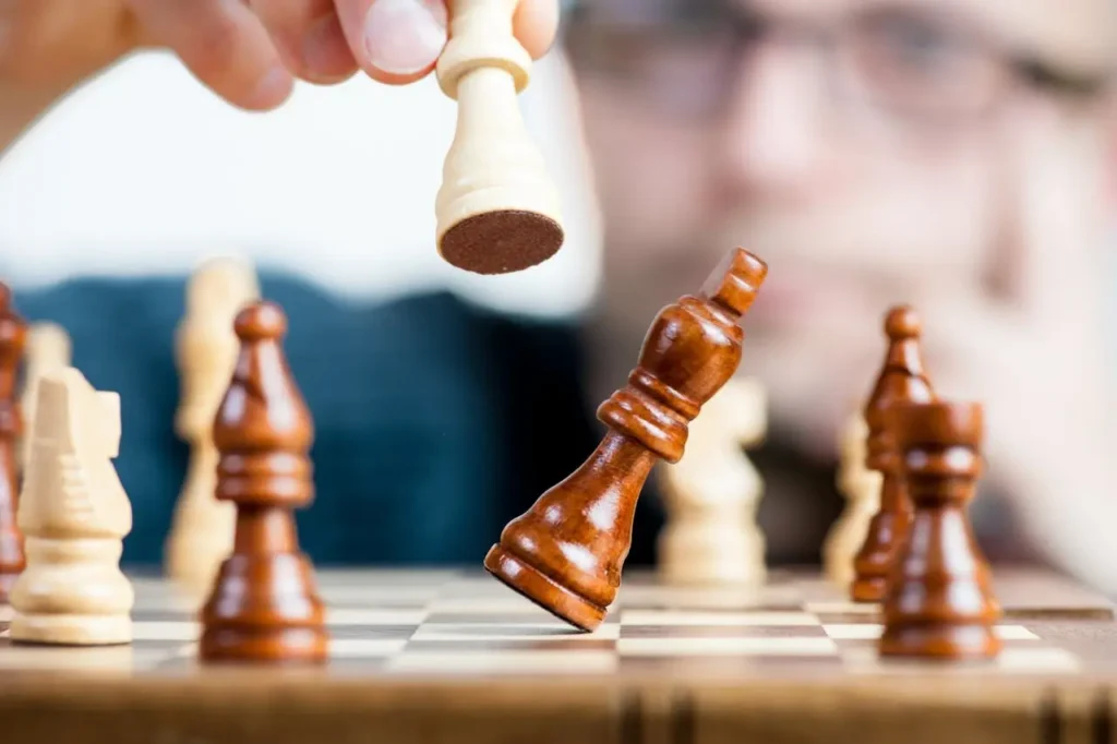 Close-up of a person strategically moving a chess piece on a board, symbolizing improved focus, memory, and mental clarity associated with brain-boosting nootropic supplements.