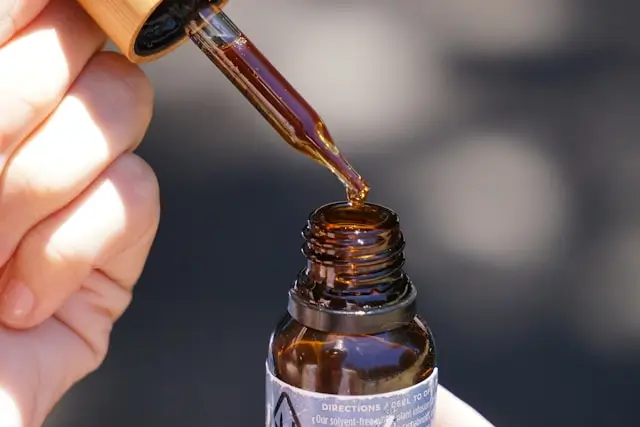 A close-up of a hand holding a serum dropper, representing the application of retinoid or active ingredients in a night skincare routine.