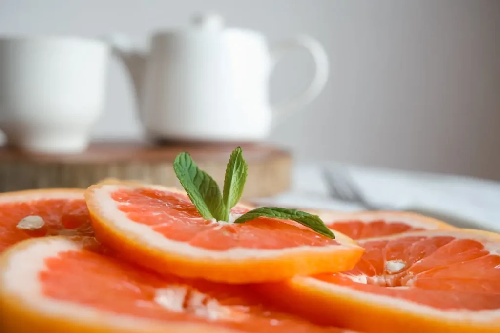 Fresh grapefruit slices with mint leaves on top, representing healthy foods linked to slow metabolism symptoms and natural ways to boost metabolism and support weight management.