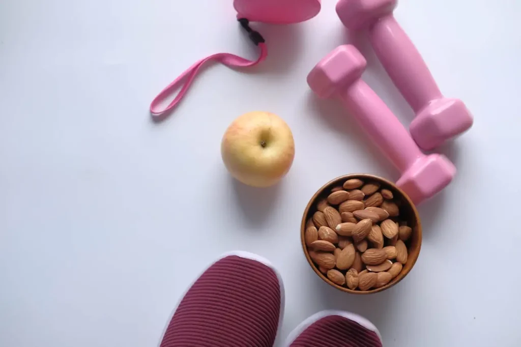 Healthy lifestyle setup with dumbbells, almonds, apple, and fitness gear, illustrating common factors behind why can’t I lose weight and hidden reasons affecting fat loss progress.