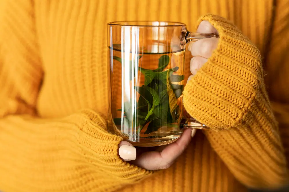 Woman holding a warm herbal detox tea in a glass mug, illustrating hormonal detox tea benefits, risks, and best herbal options for natural hormone balance and wellness support.