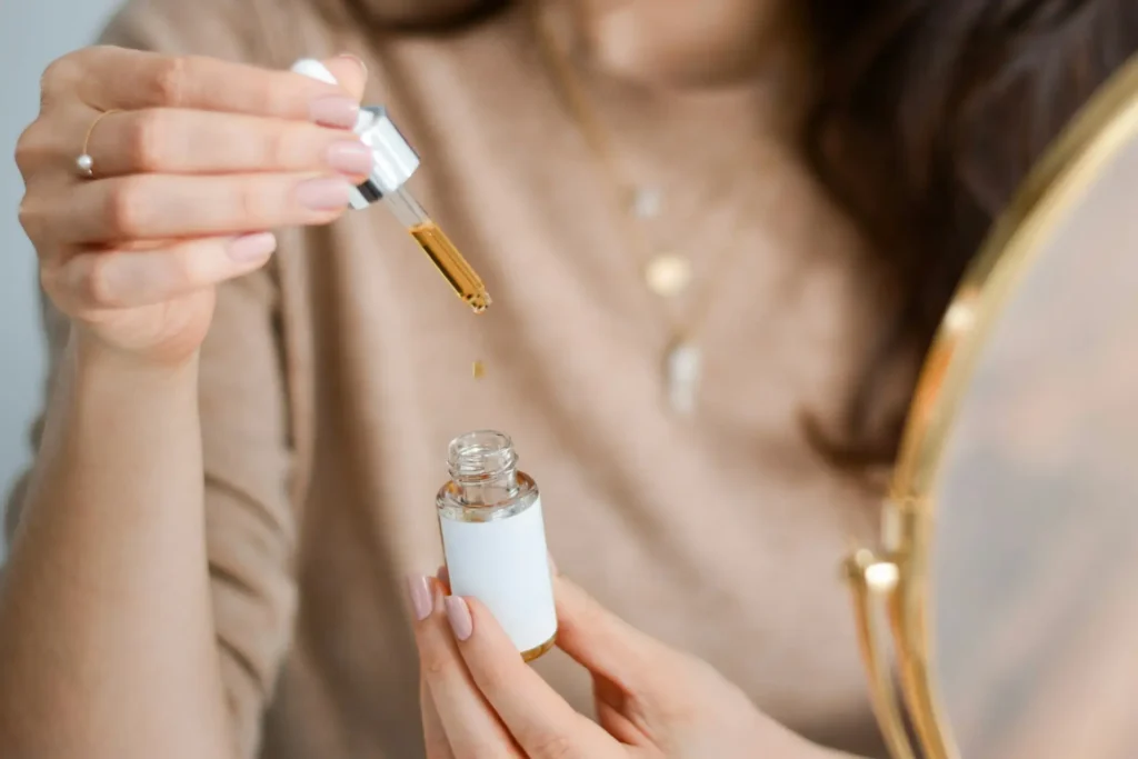 Woman applying a facial serum with a dropper to demonstrate whether hyaluronic acid should be used before or after vitamin C in a skincare routine.