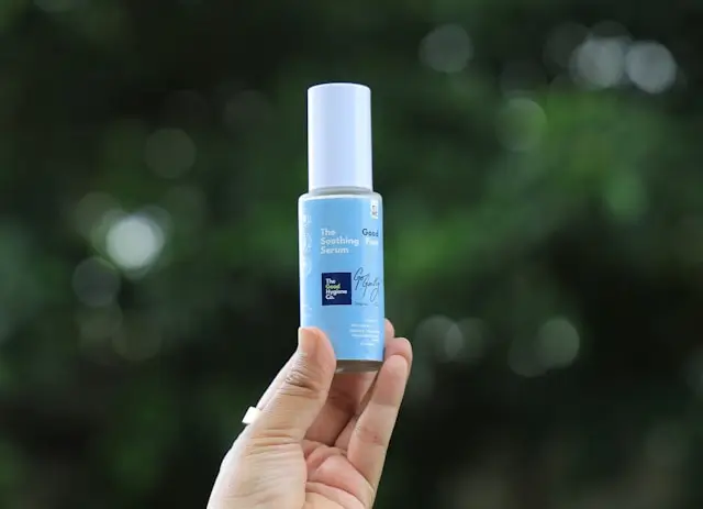 A hand holding a bottle of sunscreen, reinforcing the importance of SPF when using retinol or bakuchiol.