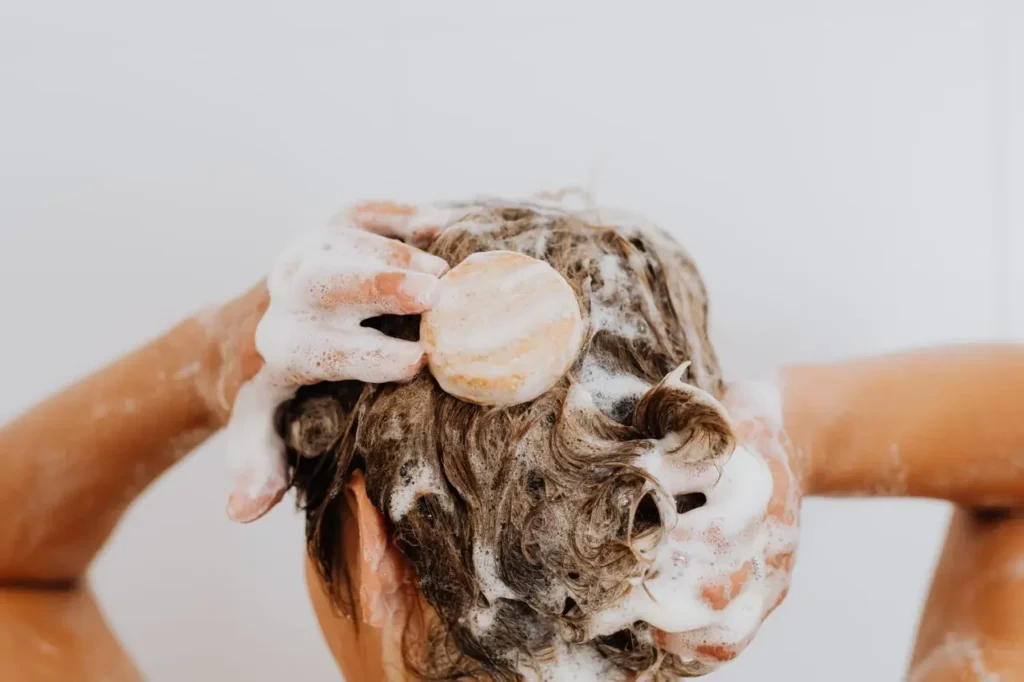 Woman washing her hair while gently massaging her scalp during a scalp cycling routine.