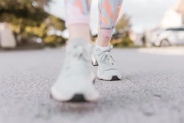 Person walking outdoors in athletic shoes, illustrating an active recovery day with gentle movement and low-intensity exercise to support recovery.