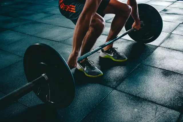 Man over 40 performing a barbell squat exercise in a gym as part of a strength training routine for healthy testosterone levels.
