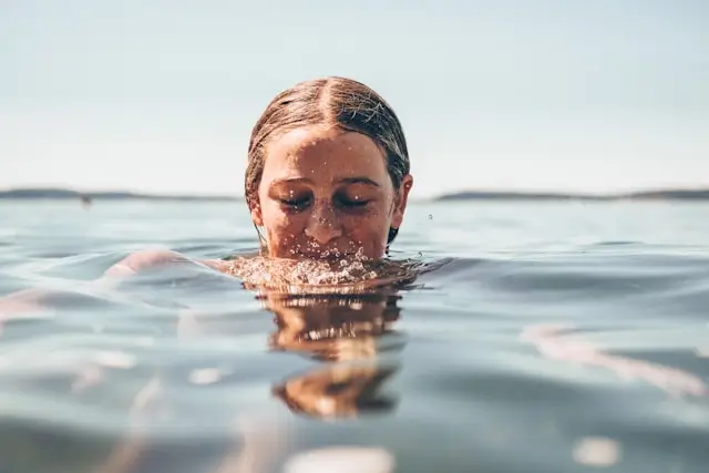Woman enjoying an open-water swim to promote lymphatic circulation, improve cardiovascular health, and support full-body fitness.