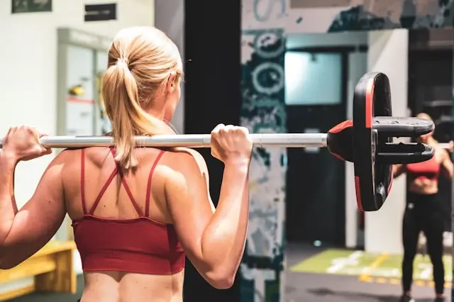 Woman lifting a barbell during a strength training workout to build muscle, improve bone health, and support healthy aging and longevity.