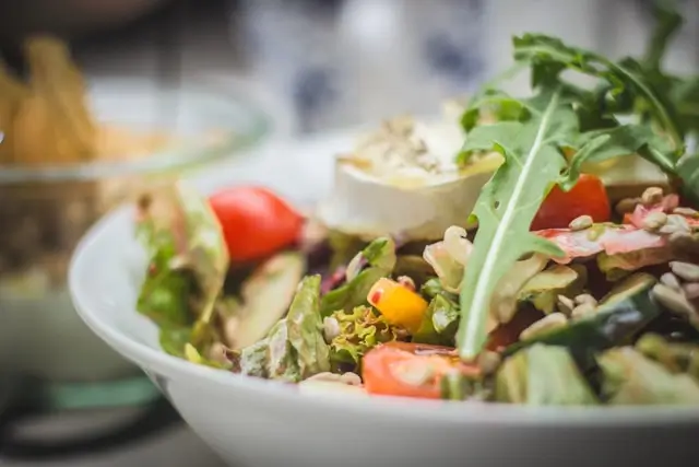 Fresh mixed salad with leafy greens, tomatoes, avocado, seeds, and other vegetables, representing a balanced approach to choosing the best diet for individual health and nutrition needs.