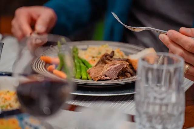Person eating a meal of grilled meat, vegetables, and other whole foods, illustrating a paleo diet for beginners focused on nutrient-dense, minimally processed foods.