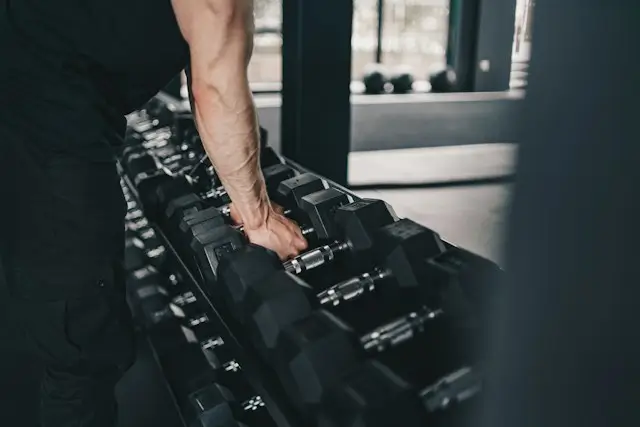 Man selecting a dumbbell from a gym rack during a strength training session, illustrating how exercise may influence testosterone levels and support male hormonal health.